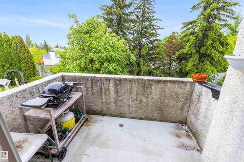 Balcony with textured concrete walls and a light-colored floor, surrounded by mature trees - 10 Everest Crescent, St. Albert, AB 