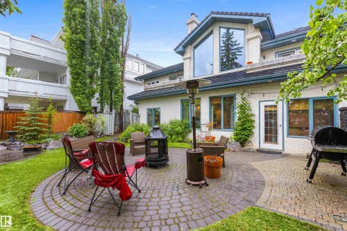 Expansive backyard featuring a circular paver patio, a rectangular paver patio, mature trees, and a wooden privacy fence - 10 Everest Crescent, St. Albert, AB 