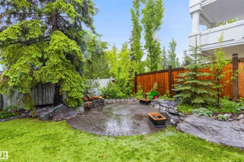 Expansive backyard featuring a circular paver patio, a manicured lawn, and mature trees - 10 Everest Crescent, St. Albert, AB 