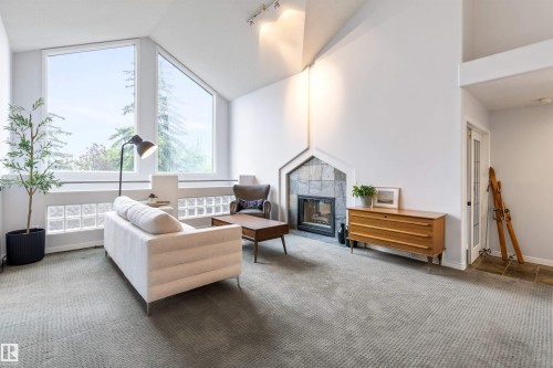 Vaulted ceilings with track lighting illuminate this living area featuring a stone-faced fireplace, expansive windows, and glass block accent windows - 10 Everest Crescent, St. Albert, AB 