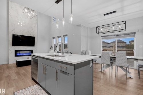 Open-concept living space featuring a modern kitchen island with an undermount sink and stainless steel dishwasher - 1616 157 Street, Edmonton, AB 