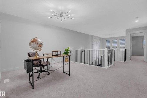 Open loft area featuring a contemporary chandelier and light gray carpeting - 1616 157 Street, Edmonton, AB 