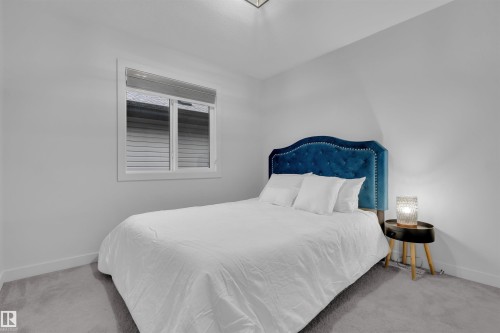 Bedroom featuring light gray walls, gray carpet flooring, a white-framed window with blinds, and white baseboards - 1616 157 Street, Edmonton, AB 