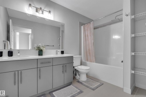 Bathroom featuring a dual vanity with a white countertop, hexagon tile backsplash, and light gray cabinetry - 1616 157 Street, Edmonton, AB 