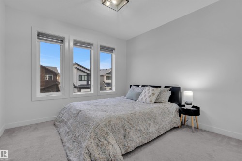 Bedroom featuring three vertical windows with white trim, light gray wall paint, and gray carpet flooring - 1616 157 Street, Edmonton, AB 