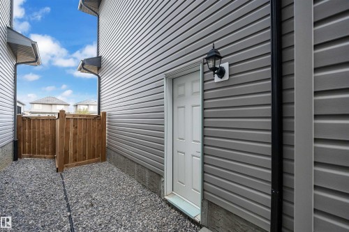 Exterior side entrance featuring horizontal grey siding, a white door, and an overhead porch light - 1616 157 Street, Edmonton, AB 