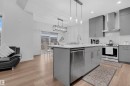 Modern kitchen featuring gray cabinetry, stainless steel appliances, a center island with sink, pendant lighting, and a white subway tile backsplash - 1616 157 Street, Edmonton, AB 