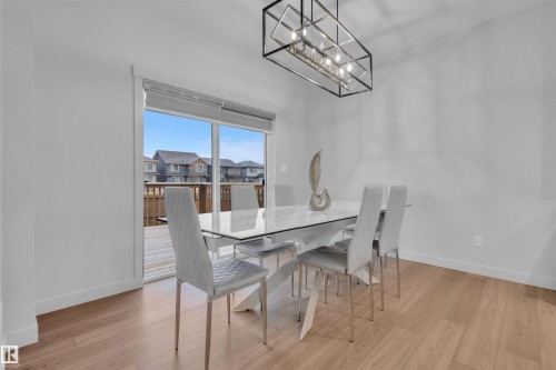 Dining area featuring light wood-finish flooring and a contemporary linear chandelier - 1616 157 Street, Edmonton, AB 