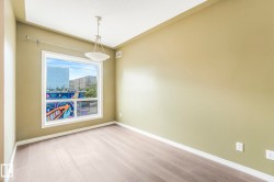 Spacious room featuring light wood-finish flooring, a contemporary ceiling light fixture, and a large window with white trim - 