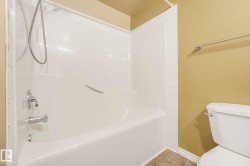 White bathtub with integrated shower, chrome fixtures, and a hand-held showerhead - 