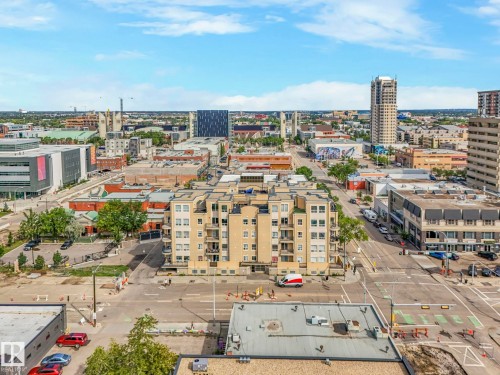 Urban landscape featuring a multi-story building with balconies, surrounded by various commercial and residential structures - 310 10606 102 Avenue, Edmonton, AB 