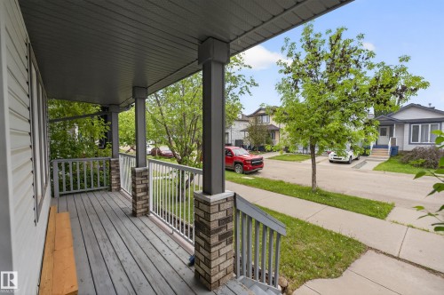 Covered front porch featuring gray wood-finish decking, white railings, and brick-look column bases - 8 Vega Avenue, Spruce Grove, AB - Outdoor With Deck Patio Veranda With Exterior