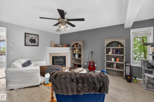 Living area featuring a fireplace with a mantel, light wood-finish flooring, a ceiling fan with integrated lighting, and a window with blinds - 8 Vega Avenue, Spruce Grove, AB - Indoor With Fireplace