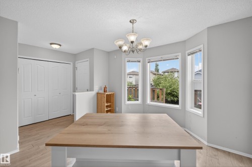 Dining area featuring a wood-finish island with white base, a multi-light chandelier, and large bay windows - 8 Vega Avenue, Spruce Grove, AB - Indoor