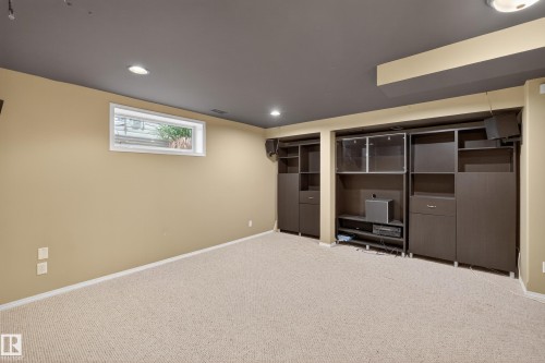 Expansive carpeted room featuring a built-in media console and shelving units - 8 Vega Avenue, Spruce Grove, AB - Indoor Photo Showing Other Room