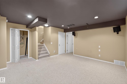 Open-concept room featuring neutral tone carpet, recessed lighting, built-in ceiling speakers, and interior access via a carpeted staircase - 8 Vega Avenue, Spruce Grove, AB - Indoor