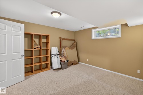 Carpeted room with a white door, a built-in light fixture, and a window providing natural light - 8 Vega Avenue, Spruce Grove, AB - Indoor