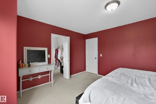 Room featuring rich red walls, neutral carpet flooring, and a ceiling-mounted light fixture - 8 Vega Avenue, Spruce Grove, AB - Indoor Photo Showing Bedroom