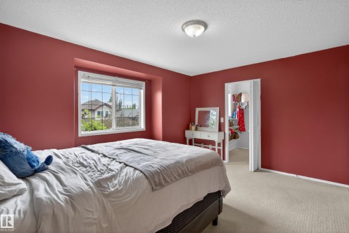 Bedroom featuring a window with exterior views, ceiling-mounted light fixture, carpeting, and a closet with bifold doors - 8 Vega Avenue, Spruce Grove, AB - Indoor Photo Showing Bedroom