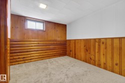 Carpeted room featuring natural wood paneling, a recessed window, and a ceiling light fixture - 