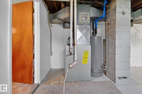Utility area featuring a furnace, water heater, and exposed ductwork - 9740 65 Avenue Nw, Edmonton, AB 