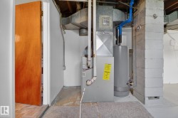 Utility area featuring a furnace, water heater, and exposed ductwork - 