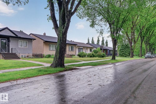 Residential street lined with mature trees, featuring a variety of single-story homes with pitched roofs and front lawns - 9740 65 Avenue Nw, Edmonton, AB 