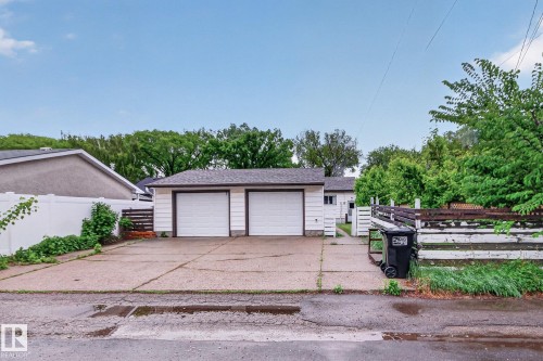 Detached two-car garage with white paneled doors and dark trim - 9740 65 Avenue Nw, Edmonton, AB 