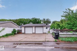 Detached two-car garage with white paneled doors and dark trim - 