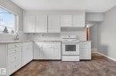 Kitchen featuring white cabinetry, stone-finish countertops, subway tile backsplash, and an electric range - 9740 65 Avenue Nw, Edmonton, AB 