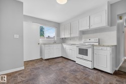 Kitchen featuring white cabinetry, light-toned countertops, a white electric range, and patterned flooring - 