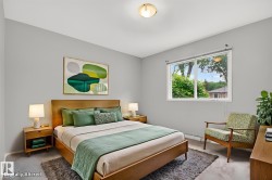 Bright bedroom with a large window, light gray walls, and light-toned carpeting - 