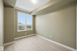 Bright interior room featuring a large window, light wood-finish flooring, and crown molding - 