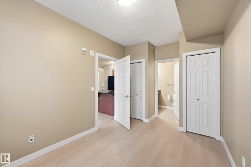 Open interior space with light wood-finish flooring, neutral wall paint, and white baseboards - 1407 9939 109 Street, Edmonton, AB 