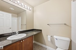 Bathroom featuring a vanity with a dark granite countertop, an undermount sink with chrome fixtures, and wood-finish cabinetry - 