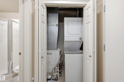 Dedicated utility closet featuring a stacked washer and dryer, adjacent to an HVAC system and water heater - 