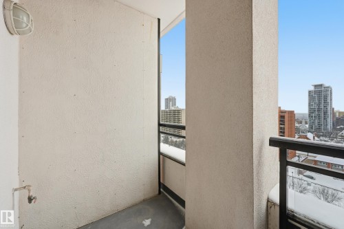 Outdoor balcony featuring a textured wall, black railing, and a wall-mounted light fixture - 1407 9939 109 Street, Edmonton, AB 