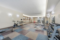 Well-appointed fitness facility featuring modular carpet tiles, recessed lighting, and wall-mounted sconces - 