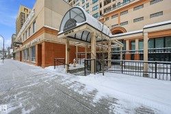 Building exterior featuring a covered entrance with an arched canopy, a stone facade, and large windows - 