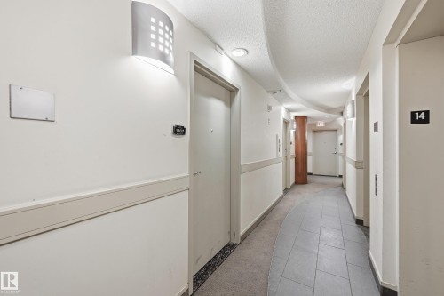 Corridor featuring contemporary wall sconce lighting, white walls, and a protective chair rail - 1407 9939 109 Street, Edmonton, AB 