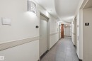 Corridor featuring contemporary wall sconce lighting, white walls, and a protective chair rail - 1407 9939 109 Street, Edmonton, AB 
