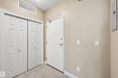 Entryway featuring a solid core door, dual bi-fold closet doors with paneling, a ceiling-mounted light fixture, and tiled flooring - 1407 9939 109 Street, Edmonton, AB 