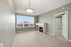 Spacious room featuring wood-finish flooring, a built-in fireplace with mantle and shelving, a multi-pane window, and an overhead decorative light fixture - 