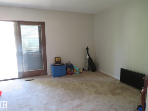 Carpeted room with a sliding glass door featuring a wood-finish frame - 10720 57 Avenue, Edmonton, AB 