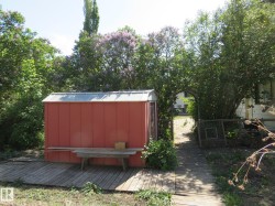 Red storage shed with a metal roof, situated on a wood-plank deck - 