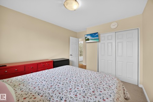 Bedroom featuring neutral wall paint, carpet flooring, a ceiling-mounted light fixture, and white bi-fold closet doors - 5216 104A Street, Edmonton, AB - Indoor Photo Showing Bedroom