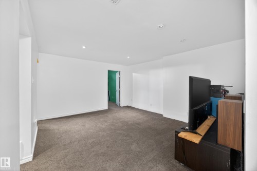 Spacious room featuring neutral carpeting, white walls, recessed lighting, and a doorway with a bright green interior - 5216 104A Street, Edmonton, AB - Indoor Photo Showing Other Room