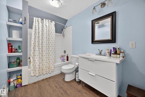 Bathroom featuring wood-finish flooring, a white subway tile tub surround, and a contemporary vanity with an integrated sink - 5216 104A Street, Edmonton, AB - Indoor Photo Showing Bathroom