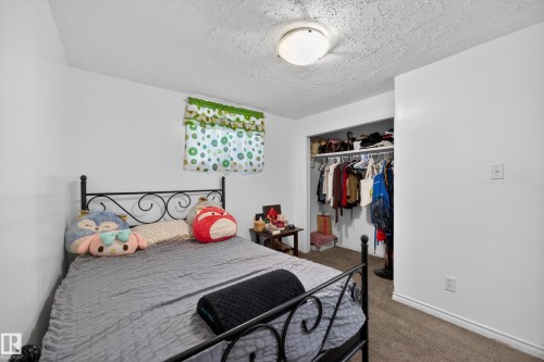 Carpeted bedroom featuring white walls, a single window with a valance, and an open closet with shelving and hanging space - 5216 104A Street, Edmonton, AB - Indoor Photo Showing Bedroom