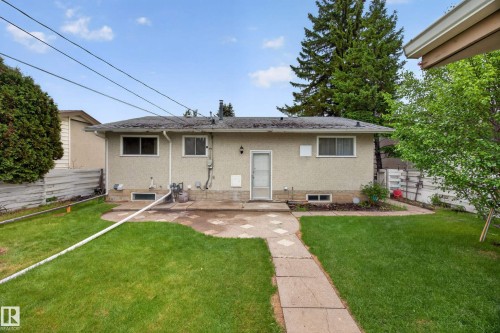 Expansive backyard featuring a manicured lawn, concrete patio, and stone paver pathway - 5216 104A Street, Edmonton, AB - Outdoor